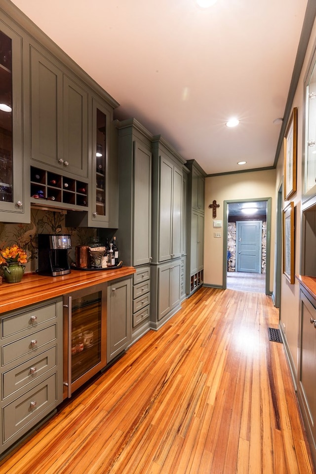 bar featuring wine cooler, gray cabinets, wooden counters, and light wood-type flooring