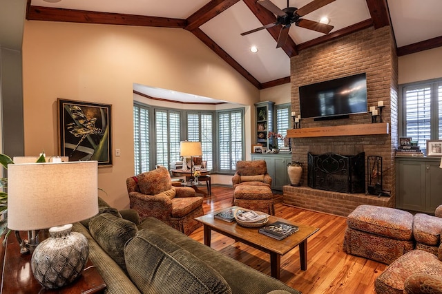 living room with high vaulted ceiling, a brick fireplace, ornamental molding, beamed ceiling, and hardwood / wood-style floors