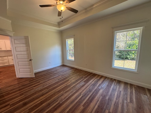 empty room featuring ornamental molding, dark hardwood / wood-style floors, ceiling fan, and a tray ceiling