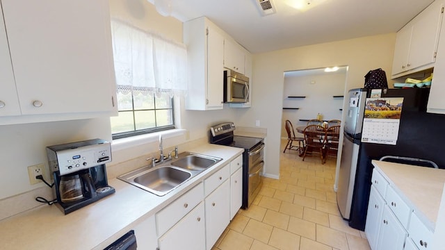 kitchen featuring light tile patterned floors, stainless steel appliances, sink, and white cabinets