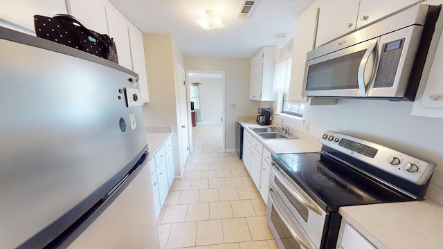 kitchen featuring sink, light tile patterned flooring, white cabinets, and appliances with stainless steel finishes