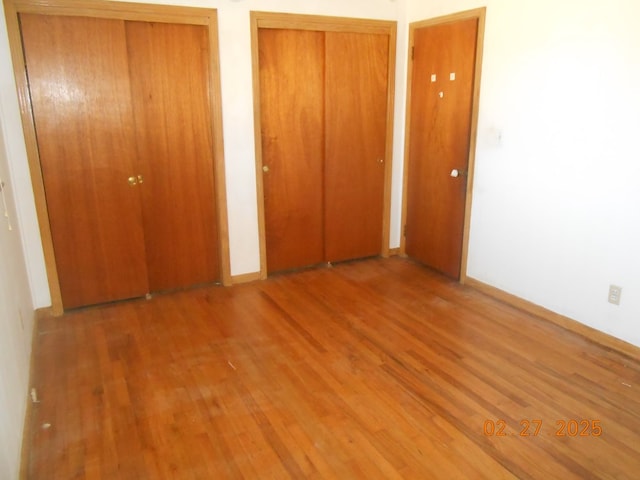 unfurnished bedroom featuring two closets and wood finished floors