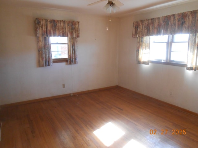 spare room featuring ceiling fan, plenty of natural light, baseboards, and wood finished floors