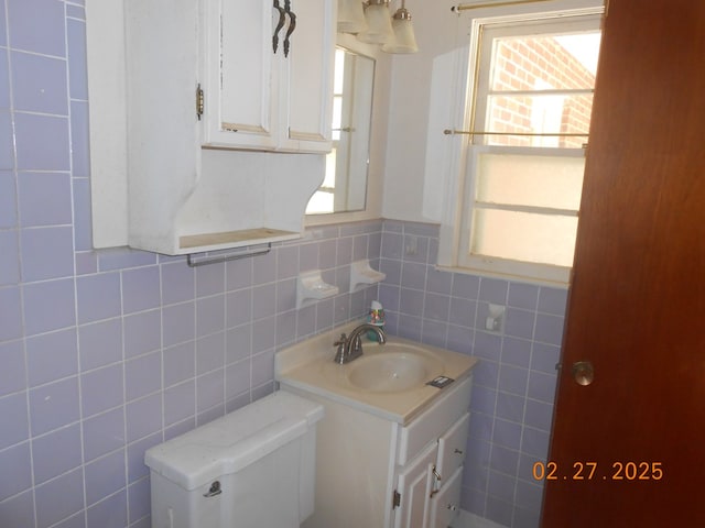 half bathroom featuring tile walls, wainscoting, and vanity