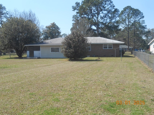 back of property featuring brick siding, a yard, crawl space, fence, and metal roof