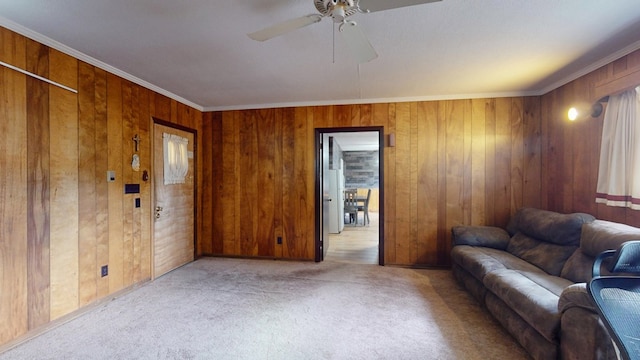 living room with crown molding, ceiling fan, wooden walls, and light colored carpet