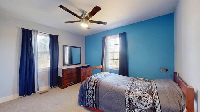 bedroom featuring baseboards, visible vents, a ceiling fan, and light colored carpet