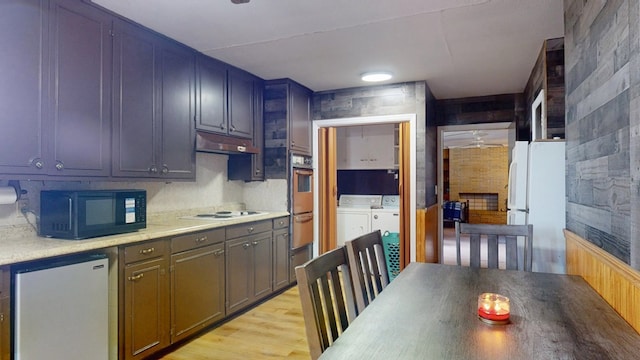 kitchen with light wood finished floors, light countertops, separate washer and dryer, white appliances, and under cabinet range hood