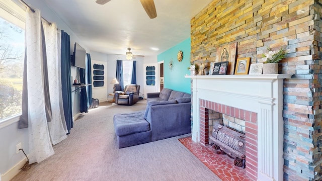 living area featuring a fireplace, a ceiling fan, and carpet flooring