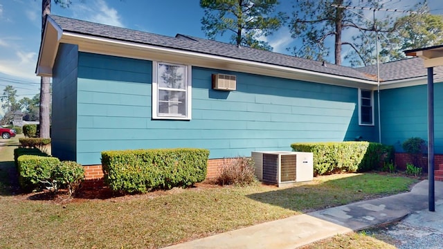 view of property exterior with roof with shingles, central AC, and a yard