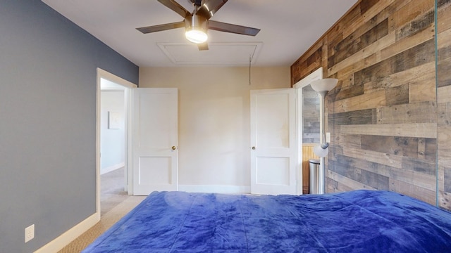 bedroom featuring attic access, light carpet, wooden walls, and baseboards