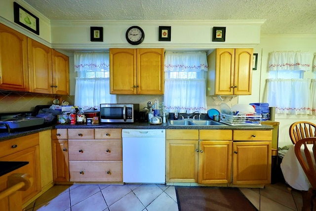 kitchen featuring a wealth of natural light, stainless steel microwave, dishwasher, and a sink