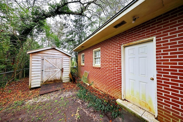 exterior space featuring an outbuilding, brick siding, fence, and a storage shed