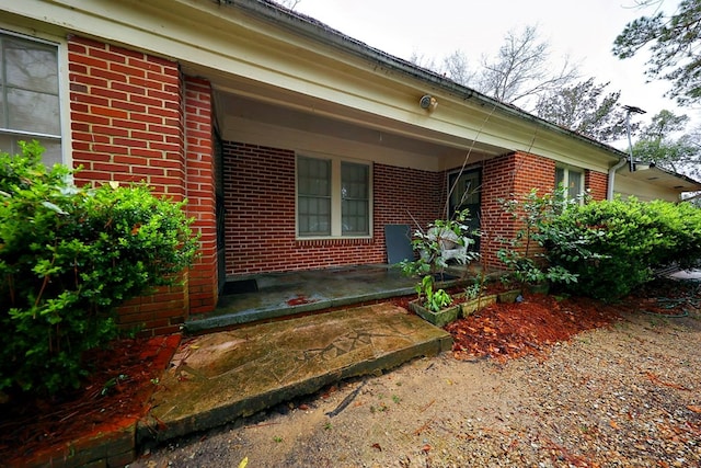 view of property exterior with covered porch and brick siding