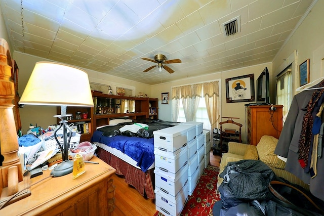 bedroom with wood finished floors, visible vents, and a ceiling fan