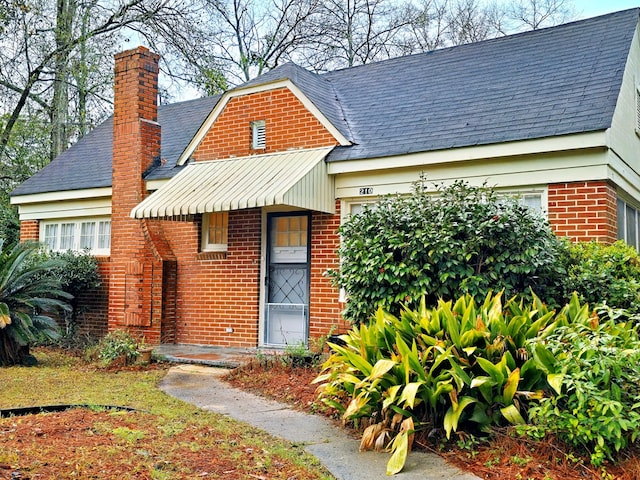 exterior space with brick siding and a chimney