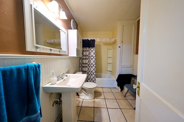 bathroom with toilet, a wainscoted wall, a sink, tile patterned floors, and shower / bath combination with curtain