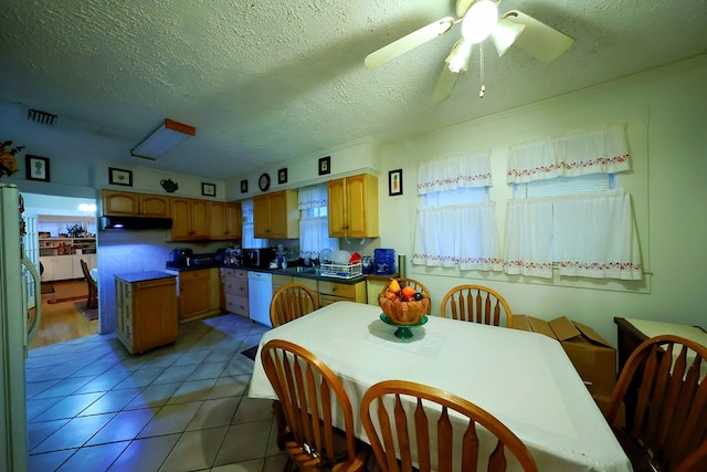 kitchen with visible vents, white dishwasher, a textured ceiling, under cabinet range hood, and light tile patterned flooring