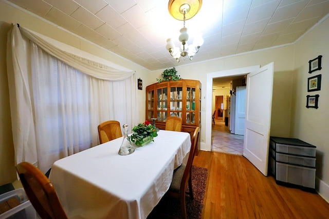 dining area with crown molding, wood finished floors, and a notable chandelier