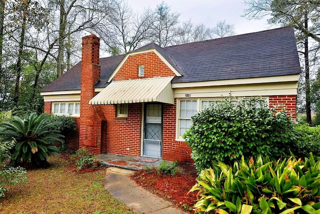 view of front of house featuring a chimney and brick siding