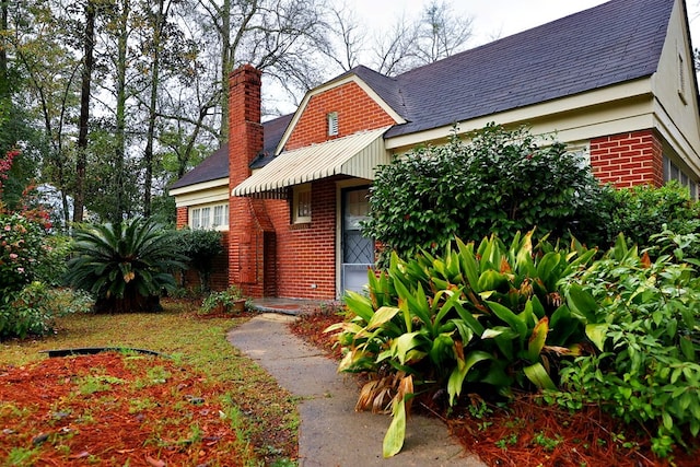 exterior space with a chimney and brick siding