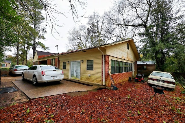 view of side of property with french doors, brick siding, and a patio area