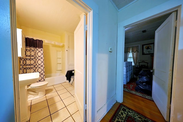 bathroom with crown molding, shower / bathtub combination with curtain, toilet, and tile patterned floors