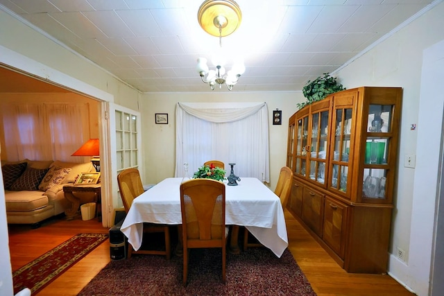 dining room featuring crown molding, a notable chandelier, and wood finished floors