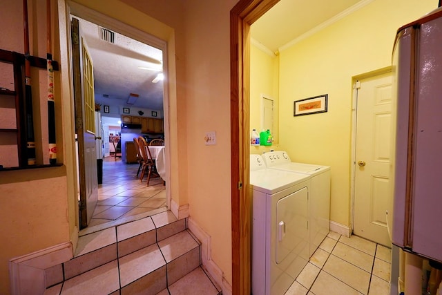 laundry area with laundry area, baseboards, crown molding, washing machine and dryer, and light tile patterned flooring