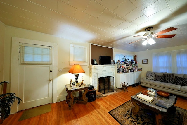 living area featuring ceiling fan, a fireplace, and wood finished floors