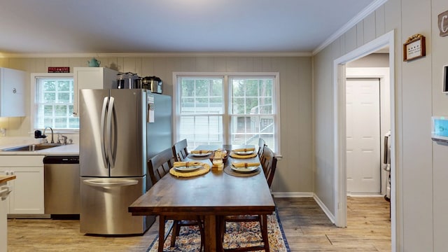 1216 Oriole Dr, Thomasville, GA 31792 - kitchen featuring appliances with stainless steel finishes, crown molding, light wood-style flooring, white cabinets, and healthy amount of natural light