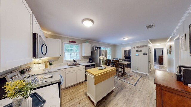 1216 Oriole Dr, Thomasville, GA 31792 - kitchen with appliances with stainless steel finishes, ornamental molding, wooden counters, light wood finished floors, and white cabinetry