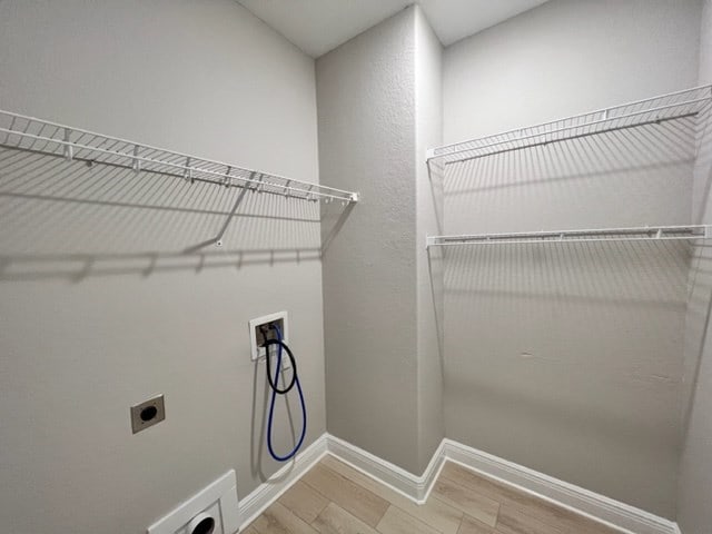 clothes washing area with baseboards, light wood-style floors, washer hookup, electric dryer hookup, and laundry area