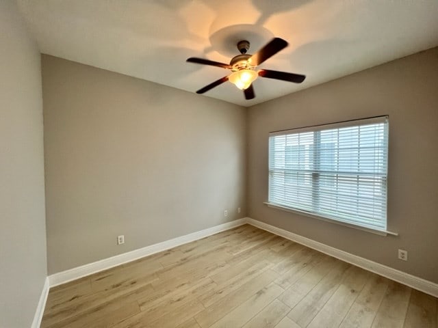 unfurnished room featuring light wood-type flooring, baseboards, and ceiling fan
