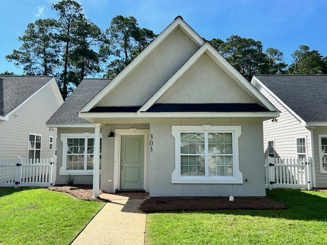 view of front of house featuring fence, a gate, a front yard, and stucco siding