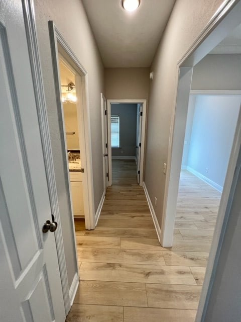 corridor featuring baseboards and light wood-style floors