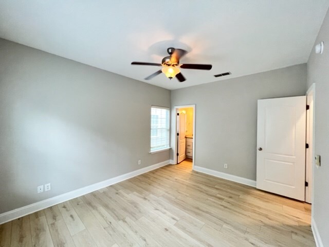 unfurnished bedroom featuring baseboards, a ceiling fan, visible vents, and light wood-type flooring