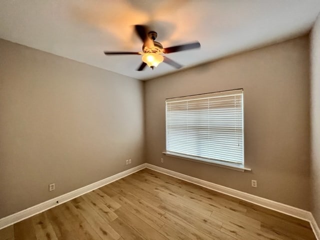 unfurnished room with wood finished floors, baseboards, and ceiling fan