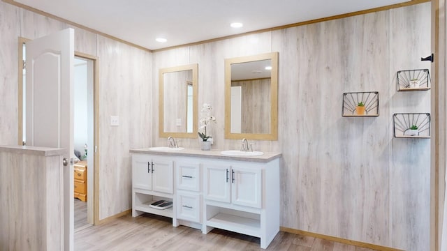 full bath with double vanity, a sink, and wood finished floors
