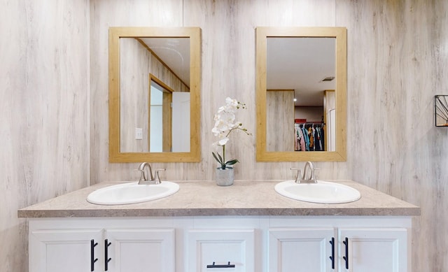 full bath featuring double vanity, a spacious closet, and a sink