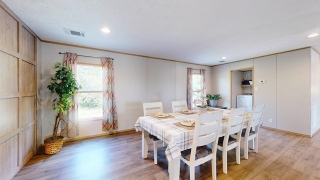 dining area with light wood-type flooring, washer / dryer, baseboards, and visible vents