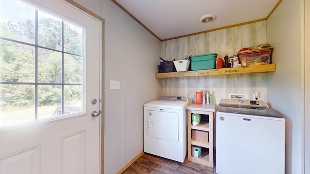 clothes washing area with laundry area, crown molding, wood finished floors, washer and dryer, and wooden walls
