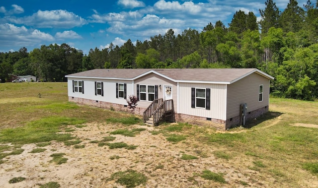 manufactured / mobile home with crawl space, a forest view, and a front yard