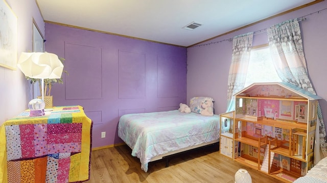 bedroom featuring visible vents, ornamental molding, and wood finished floors