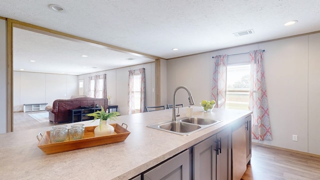 kitchen with a sink, light wood-style flooring, recessed lighting, and a textured ceiling