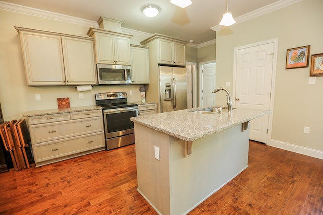 kitchen with sink, appliances with stainless steel finishes, cream cabinets, and light stone counters