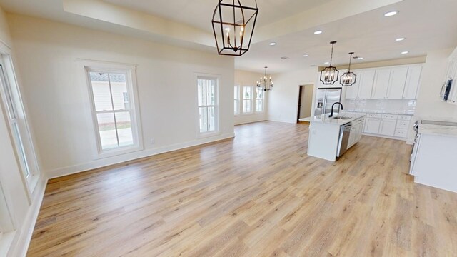 kitchen with pendant lighting, sink, appliances with stainless steel finishes, an island with sink, and a chandelier