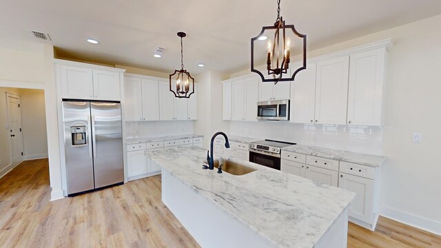 kitchen with hanging light fixtures, appliances with stainless steel finishes, sink, and white cabinets