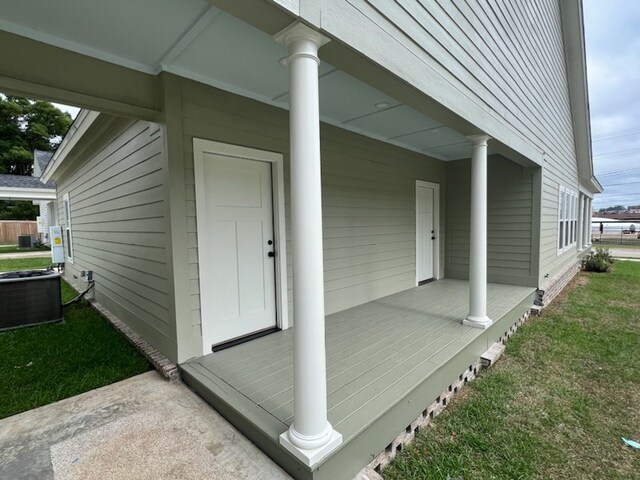 entrance to property featuring a porch, a lawn, and central air condition unit