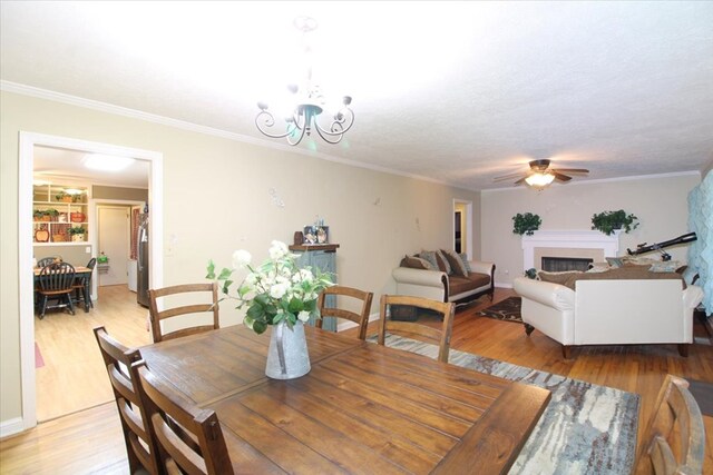 dining space with crown molding, ceiling fan with notable chandelier, light hardwood / wood-style flooring, and a textured ceiling